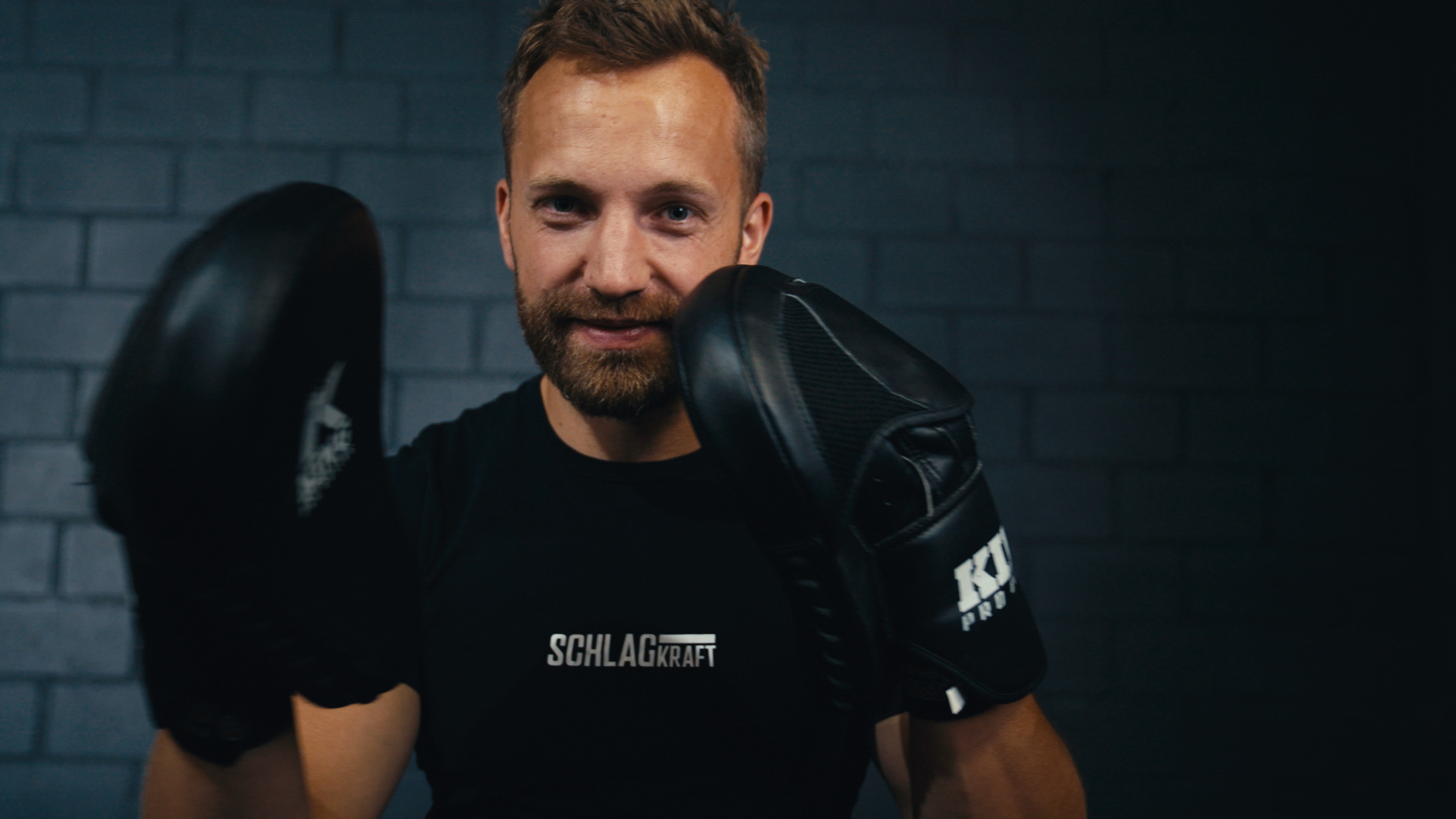 Andrej Waldenberger mit Boxhandschuhen in Deckung vor dunkler Backsteinwand