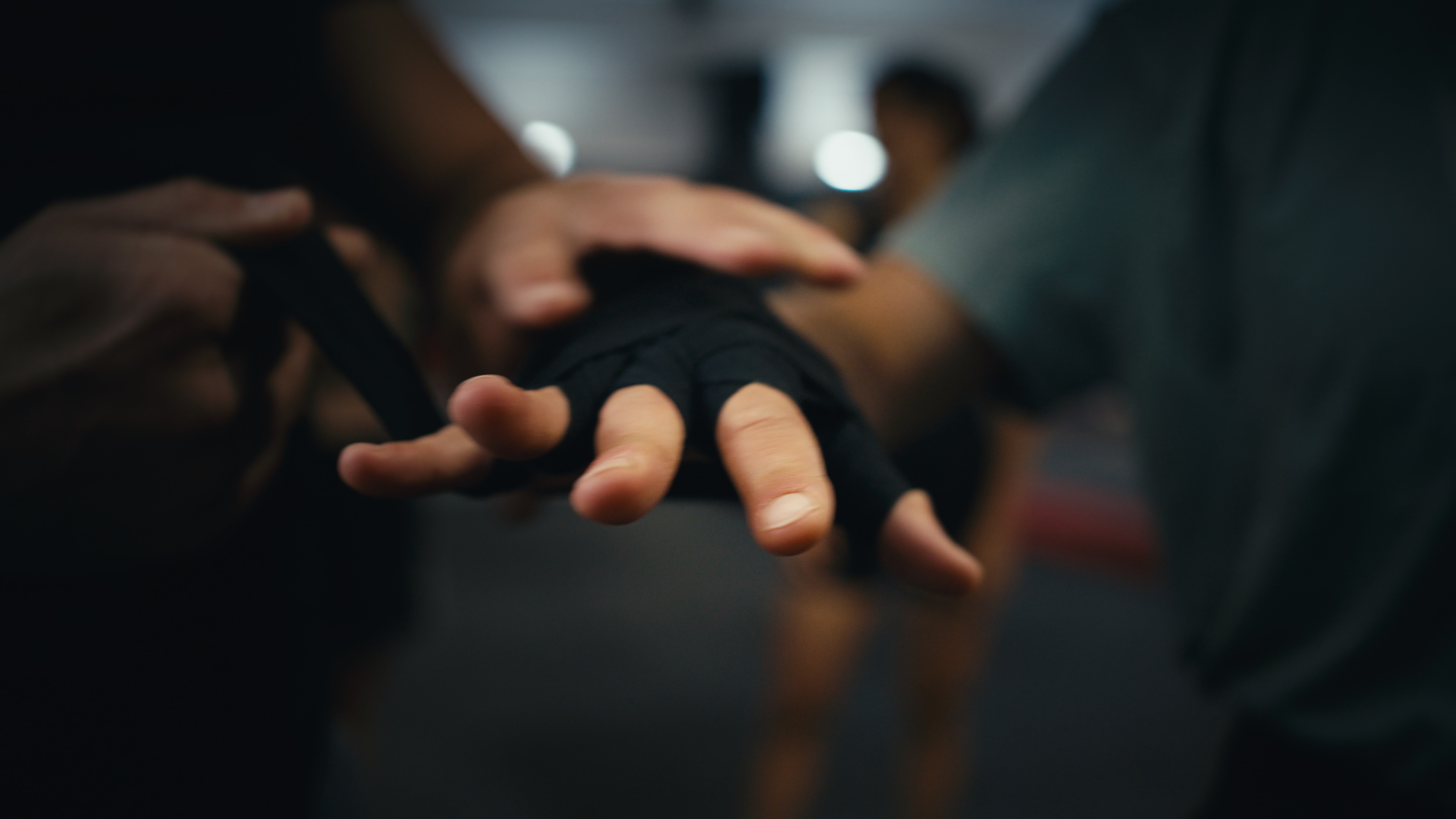 Hand mit angelegter Boxbandage, im Hintergrund die Trainingsgruppe