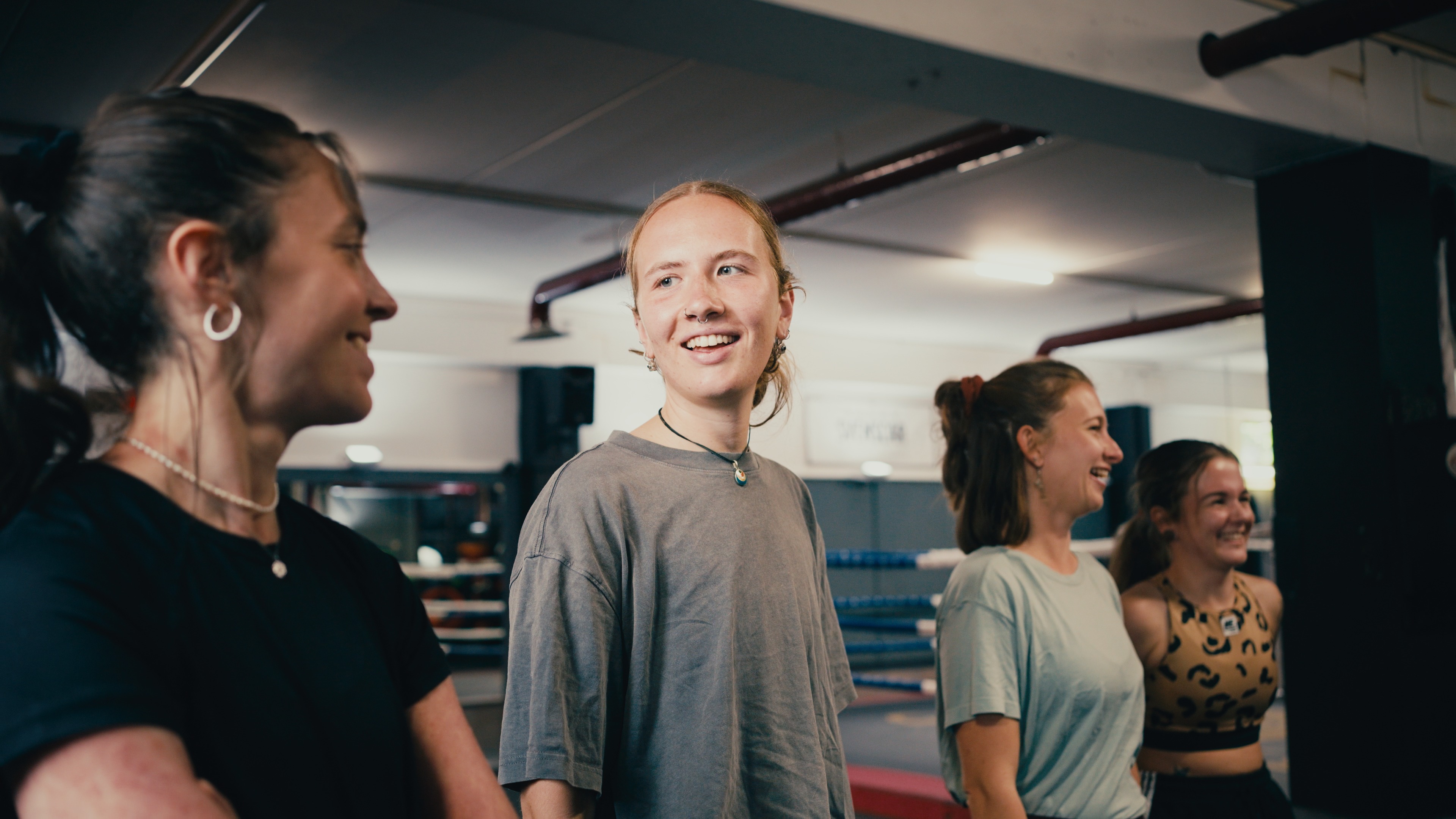 Lachende Teilnehmerinnen einer Teambuilding-Einheit im Boxgym